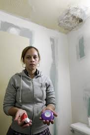 Maribel Baez in her mold-covered bathroom holding her asthma medication