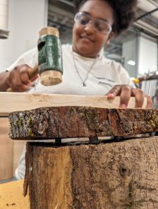 Yoheidy Feliz connecting a red maple slab to a slanted locust base, with dowels and wood glue.
