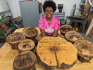 Yoheidy sits with her series of laser engraved wood slabs.