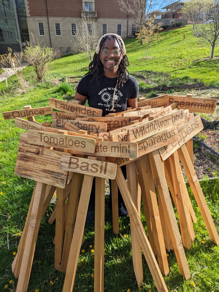 Sam Samuel '26 with 37 laser-engraved signs for the Envi Center gardens. This project was sourced from three 24" sugar maple logs from a fallen tree in Hopkins Memorial Forest,