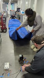 Iterating with a variety of fans to explore billowing effects for the dancer's fabric. From left to right: Kyle Yager, Tsedaye Makonnen, and Jason Mativi. Out of frame: David Keiser-Clark.