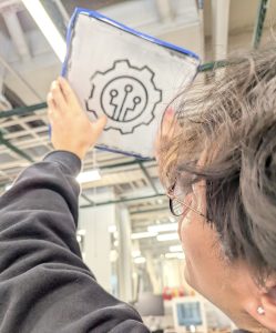Stephen Sabio '28 examining the first attempt to use the laser engraver to do a reusable skill stencil.