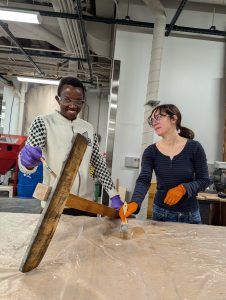 Irenee Niyibaho and Isabella Penna-Ward preparing to paint the laser engraved words in the signs