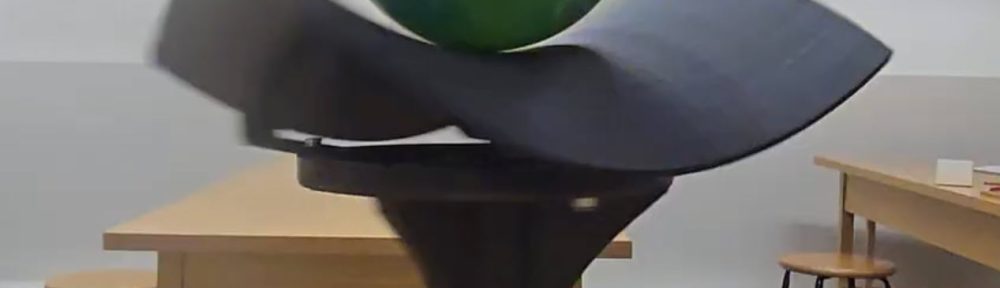 A still photo from a video of a sweeping hyperbolic paraboloid with a ball resting right at its unstable center. Photo courtesy of Brough Morris.