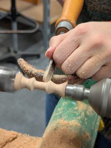 A close up of using the wood lathe and lathe chisels to turn the 14 tuning bulges.