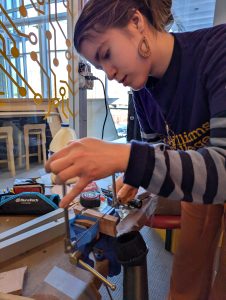 Sabrina using a coping saw to shape the bridge for the lyre.