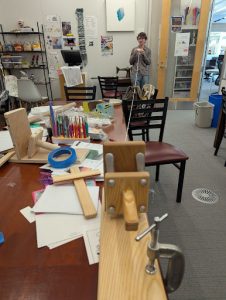 Meyer rope jig in use with Ari Merrill '28 holding the ends of the loops of shrink-wrap.