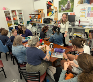 Participants in the Berkshire Satellite Reef Project's crochet workshop, led by Led by Rae Bravo ’28, Annie Trucano ’29, and Professor Amy Holzapfel (standing).